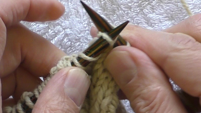 The new stitch is on the left hand needle and is being pushed onto the body of that needle before the right hand needle is removed from the old stitch.