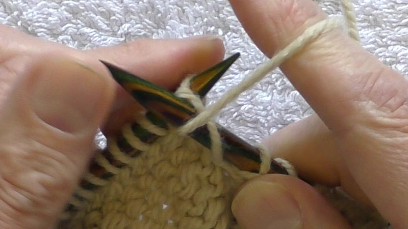 Loop of yarn on left hand needle being pulled through the stitch on the right hand needle towards the back.
