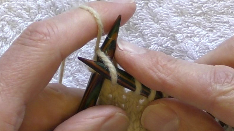 Left needle being inserted from left to right into the back of the first stitch on the right hand needle with the left needle passing behind the right needle. The yarn is held behind the work.