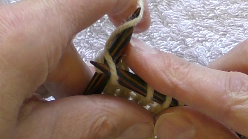 Yarn being wrapped round the left needle. Starting at the back, passing to the left of the needle, round the front and returning to the back on the right side of the needle.