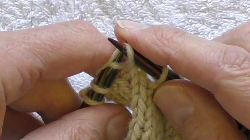 The working yarn being pulled through the stitch held on the right hand needle.