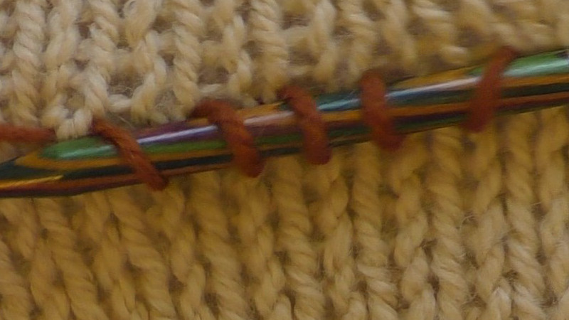 Row of new stitches lying on a needle across the public (right) side of fabric.