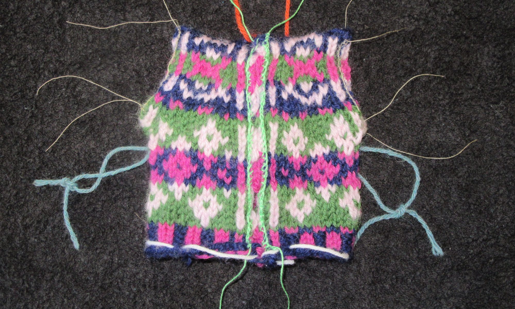 The waistcoat for the Introduction to stranded knitting tutorial after the steeks have been reinforced using crochet reinforcement. The front steek has been reinforced with crochet cotton, the armhole steeks with sewing thread, showing that the type of thread used is not important.