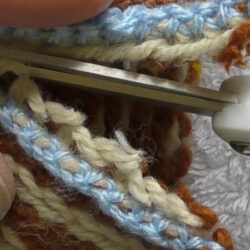 A steek reinforced using crochet that is being cut with scissors